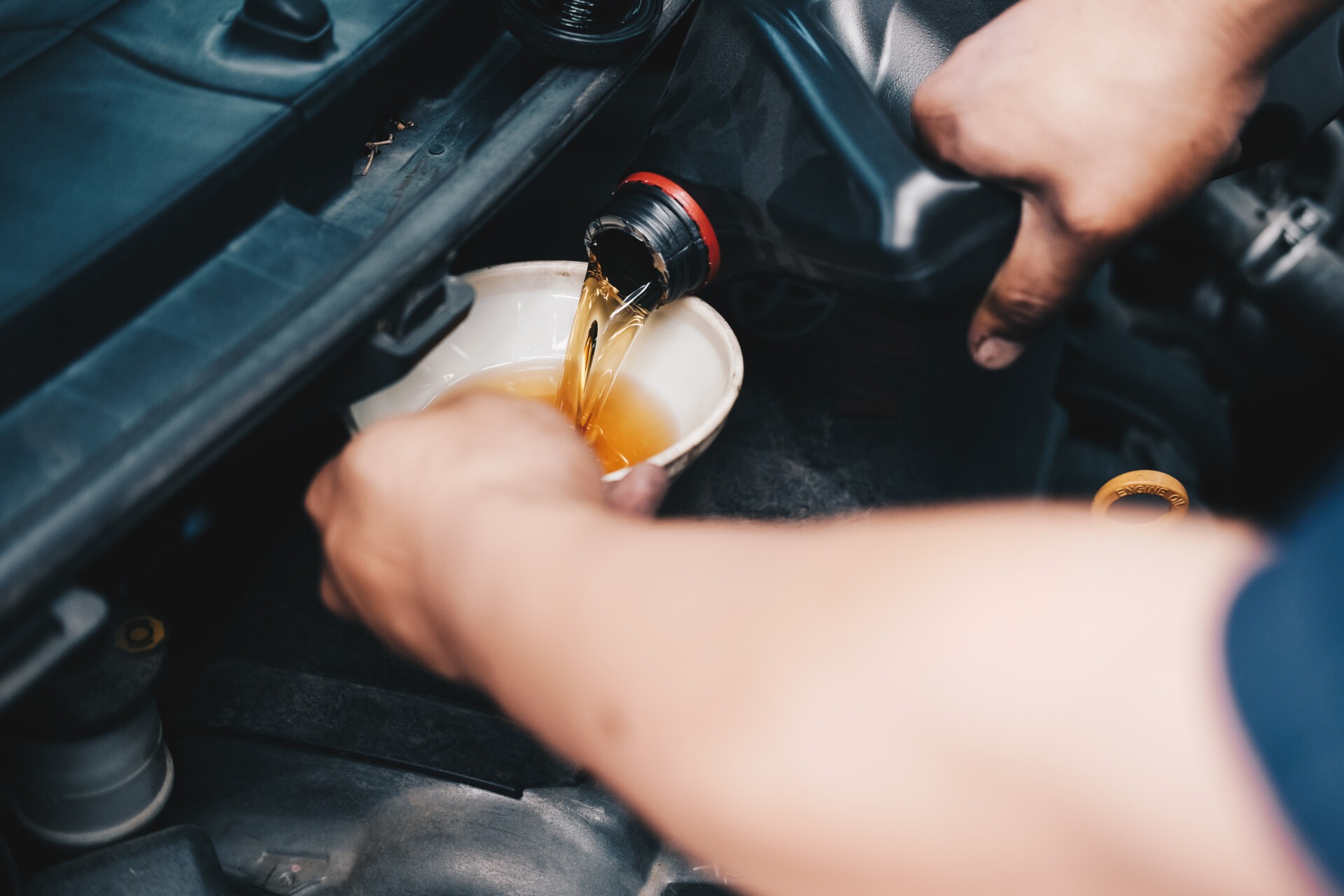 mechanic pouring oil to vehicle engine. serviceman changing moto